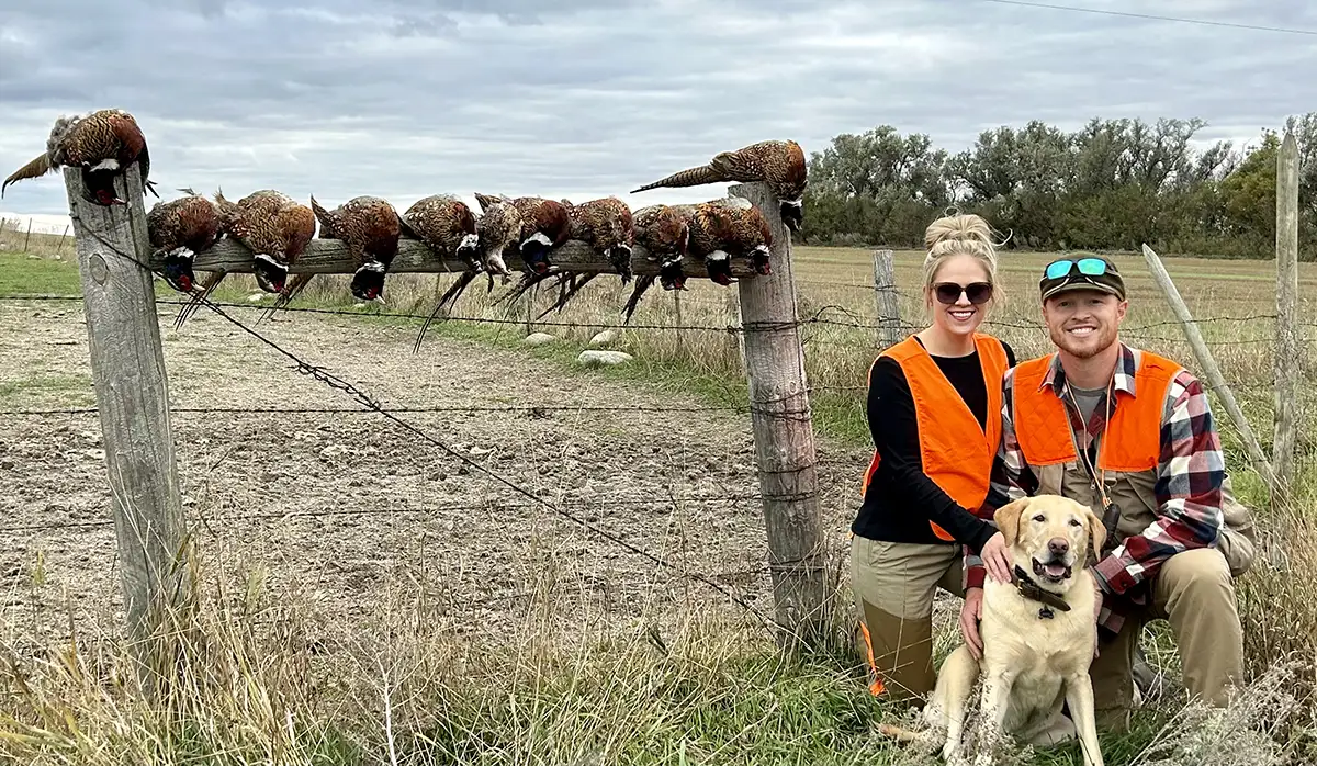 Katie and Wade with their hunting dog and pheasants